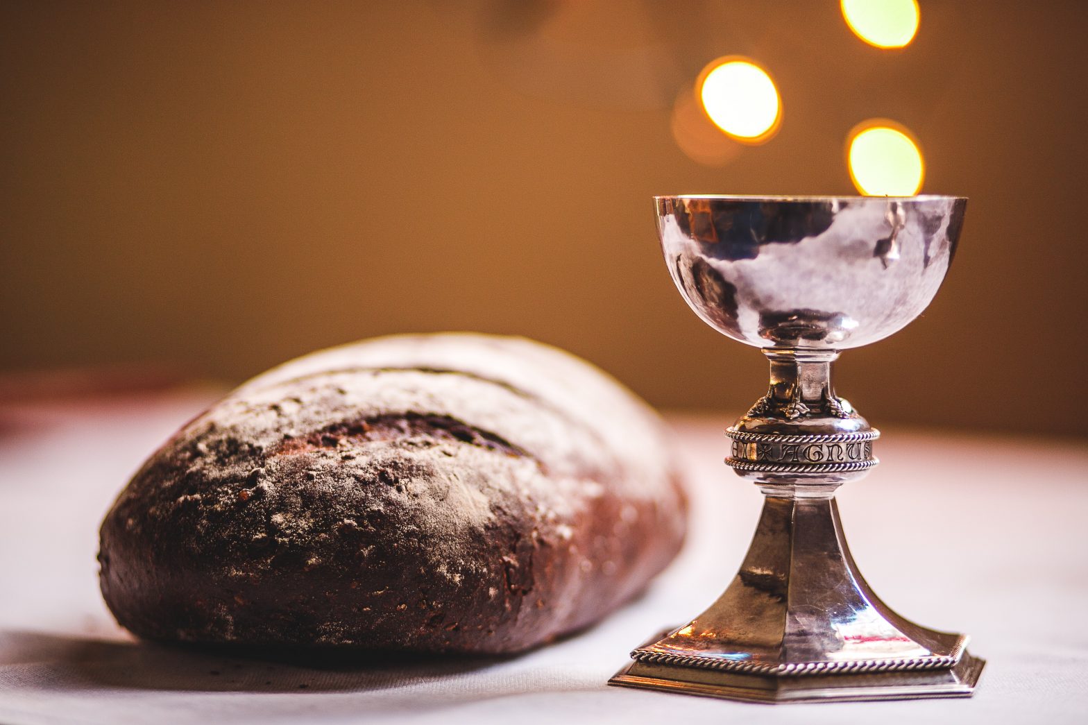 A silver chalice beside a loaf of bread.